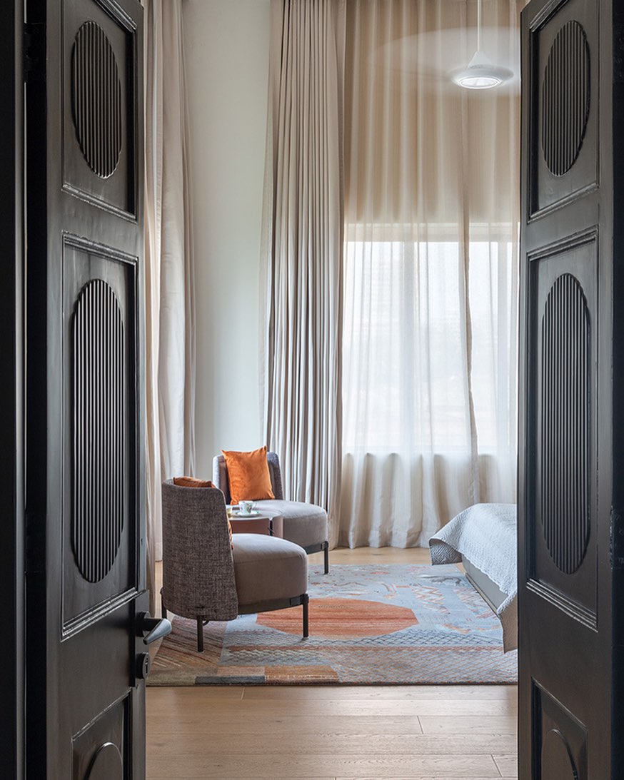 Striking double-height curtains create a sense of grandeur, making the master bedroom both dramatic and cozy.