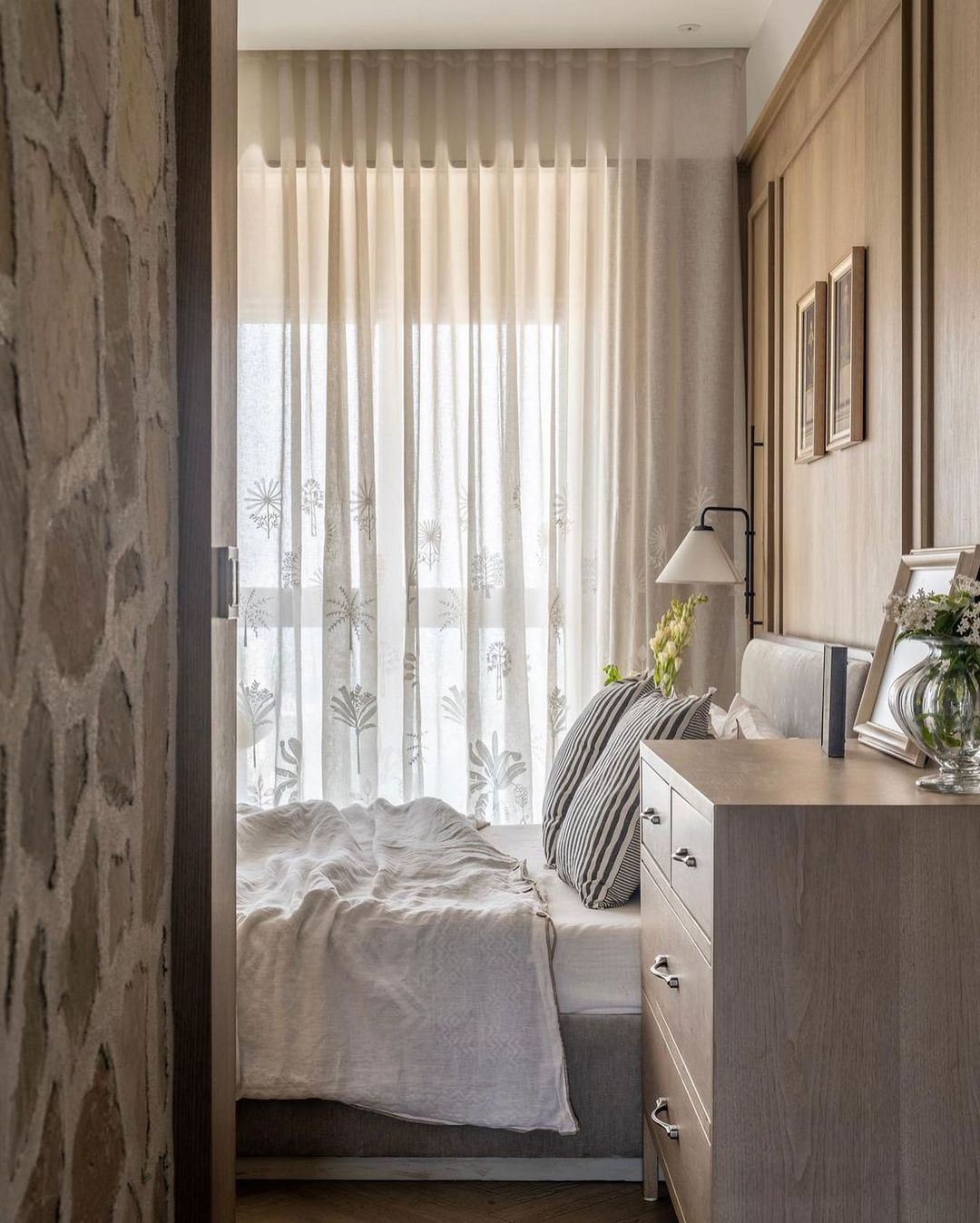 A curtain featuring embroidered Palm Trees in a bedroom.